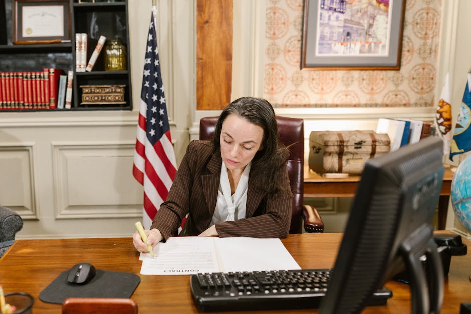 Female attorney in a law office signing legal documents at her desk, surrounded by legal books and symbols of justice