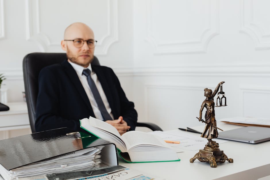 Bald lawyer in office sitting with legal documents and Justice statue